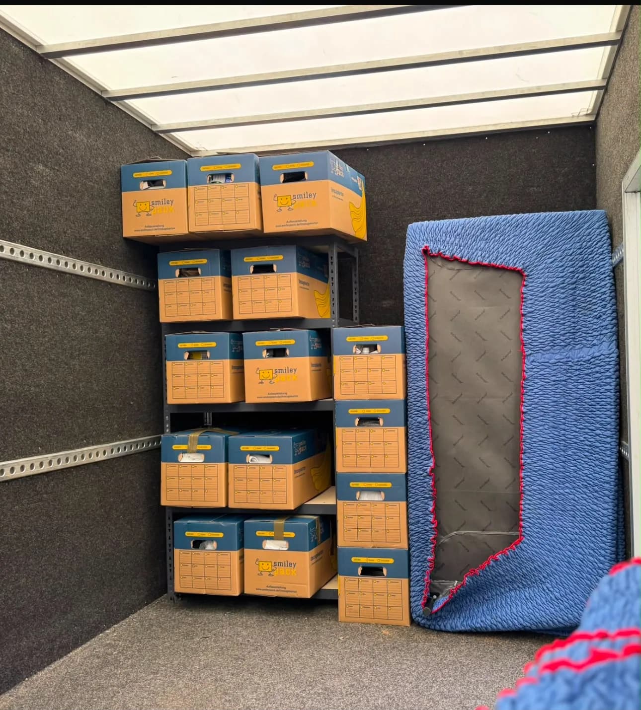 Beladener Umzugswagen mit gestapelten Umzugskartons und einer in eine Decke verpackten Matratze