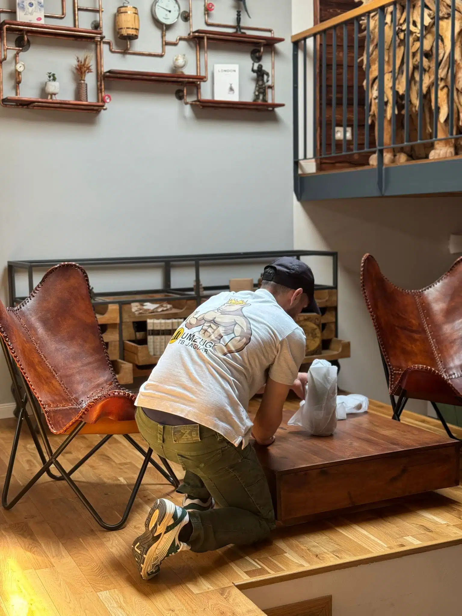 Eine Person in hellem T-Shirt und Mütze kniet am Couchtisch